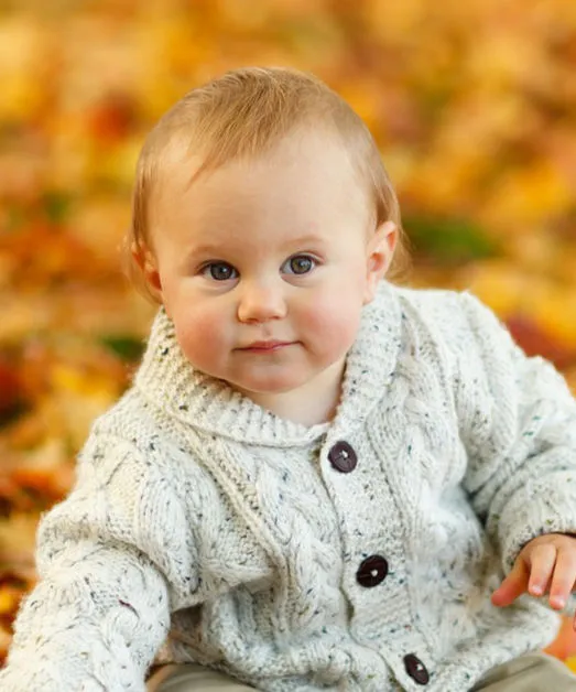 Kleinkind sitzt auf Herbstlaub